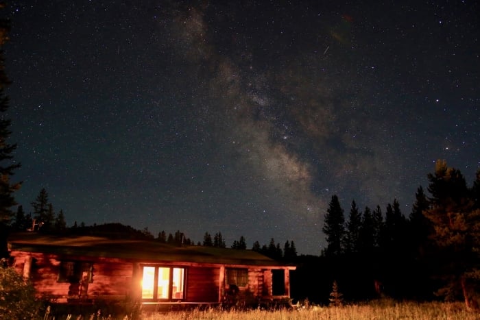 Cabin with lights inside against starry sky