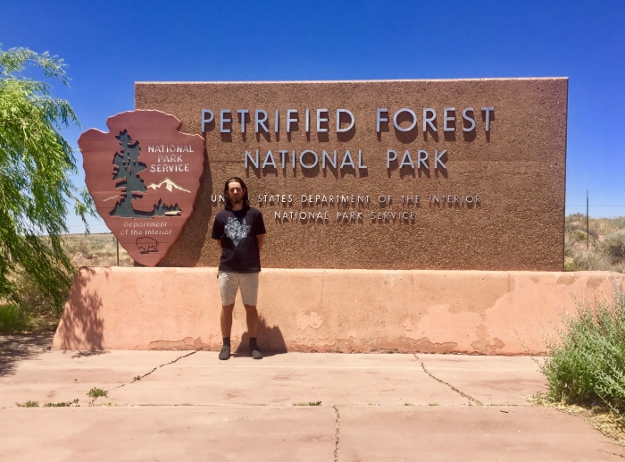 Man standing with Petrified Forest National Park sign