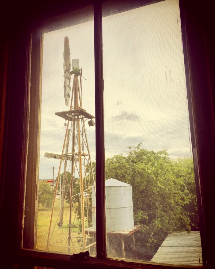 windmill and water tank through a window with a vintage photo filter