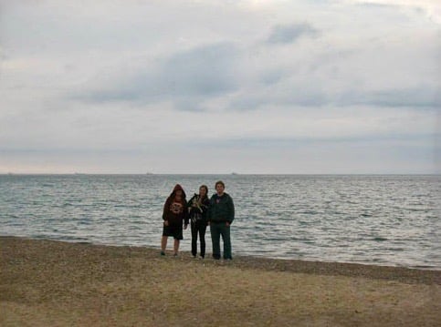 Three people standing by Lake Huron.