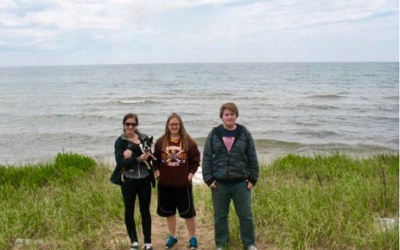 Three people standing by Lake Huron.