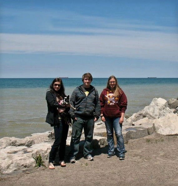 Three people standing by a large body of water.